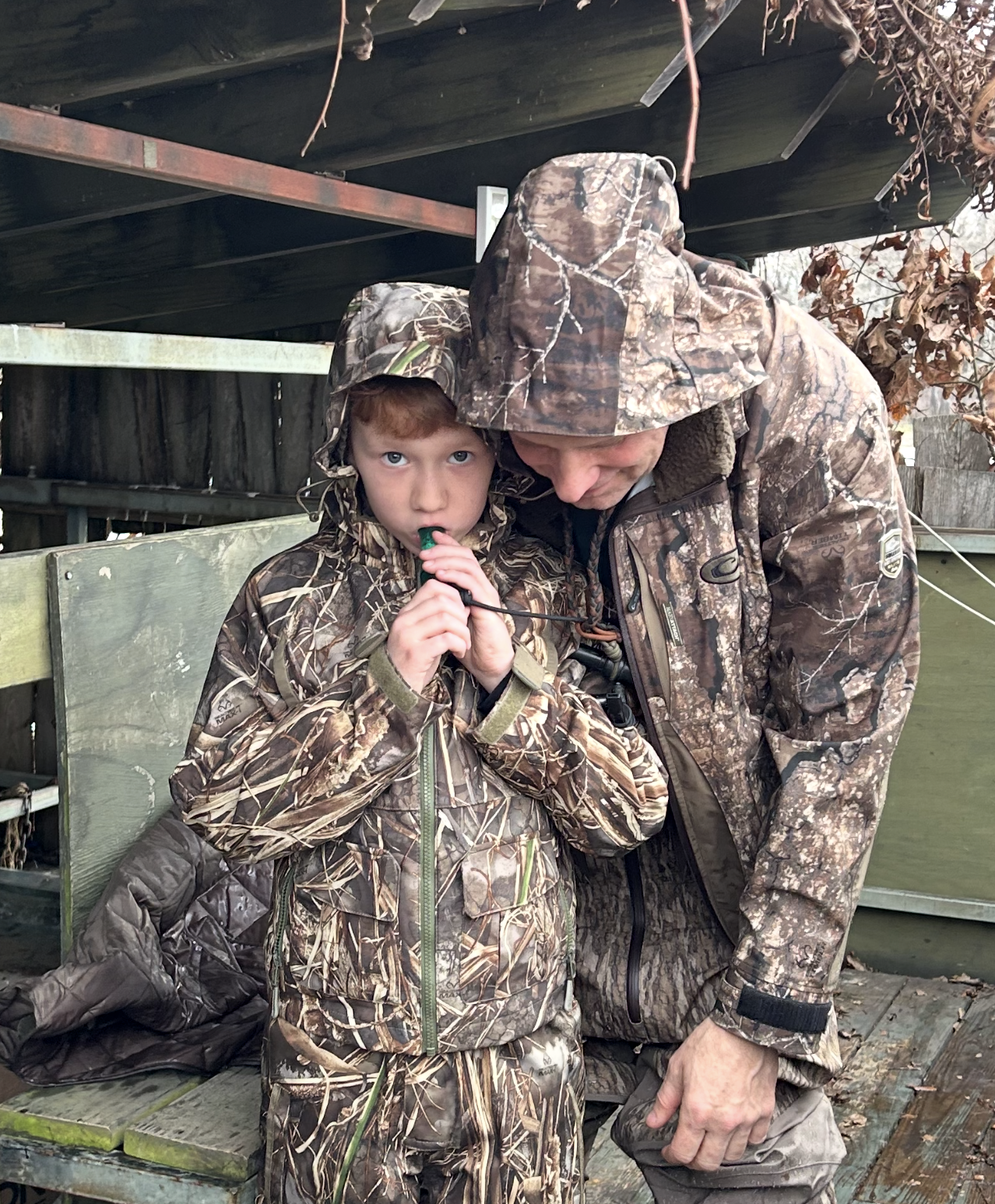 Stewart Whaley teaching his 10-year-old son how to blow a duck call in a duck blind during Arkansas waterfowl season