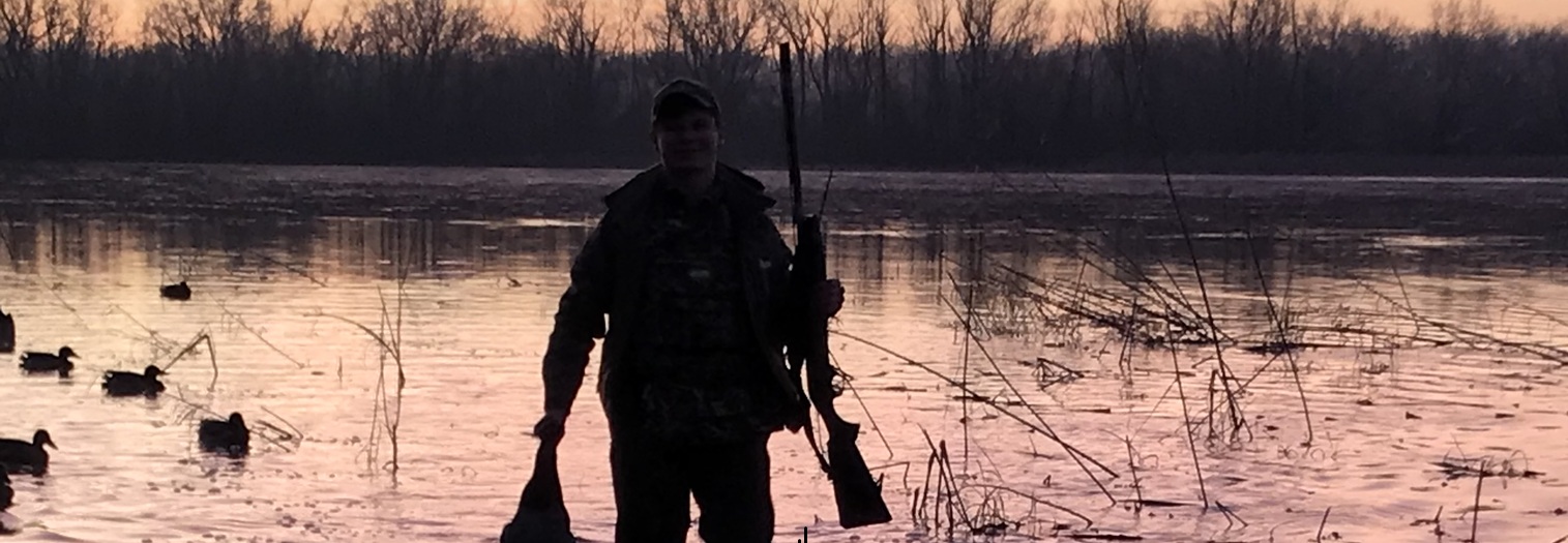 Duck hunter at dusk retrieving duck.